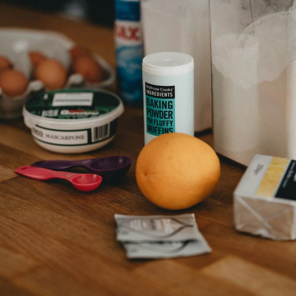 Eggs, mascarpone, baking powder, a lemon, butter, measuring spoons, and packets on a wooden countertop, with a white container and cleaning spray in the background. | outdoorsurvivors.com Eggs, mascarpone, baking powder, a lemon, butter, measuring spoons, and packets on a wooden countertop, with a white container and cleaning spray in the background | outdoorsurvivors com